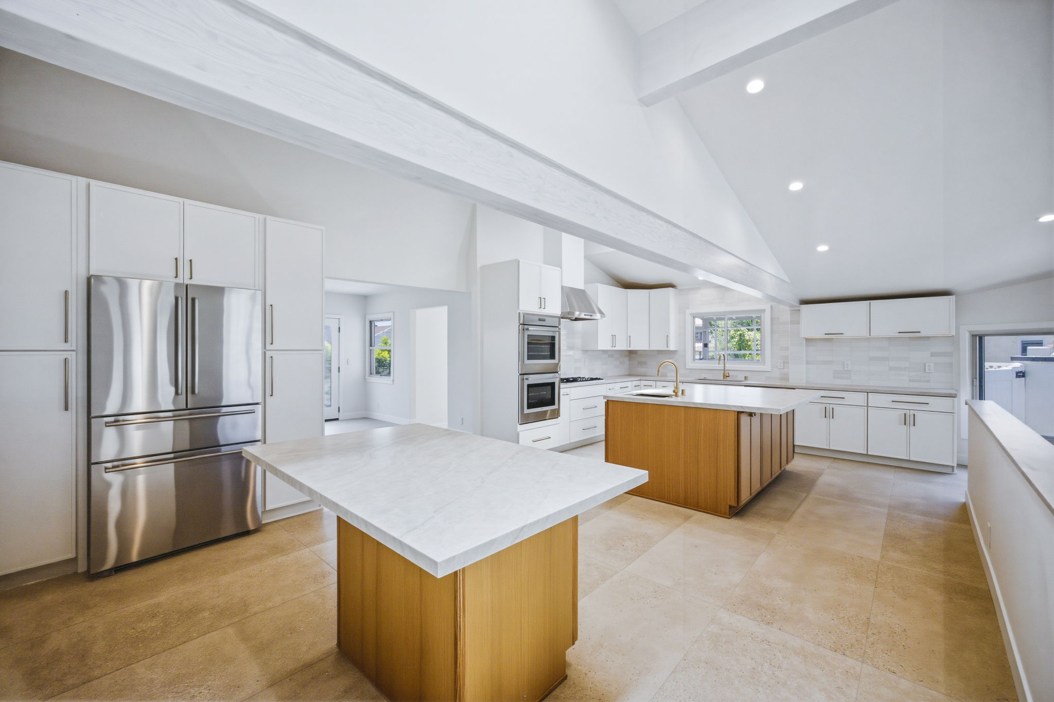 - Oasis Builders, Inc. Bright modern kitchen with white cabinets, marble countertops, and a wooden island at center.